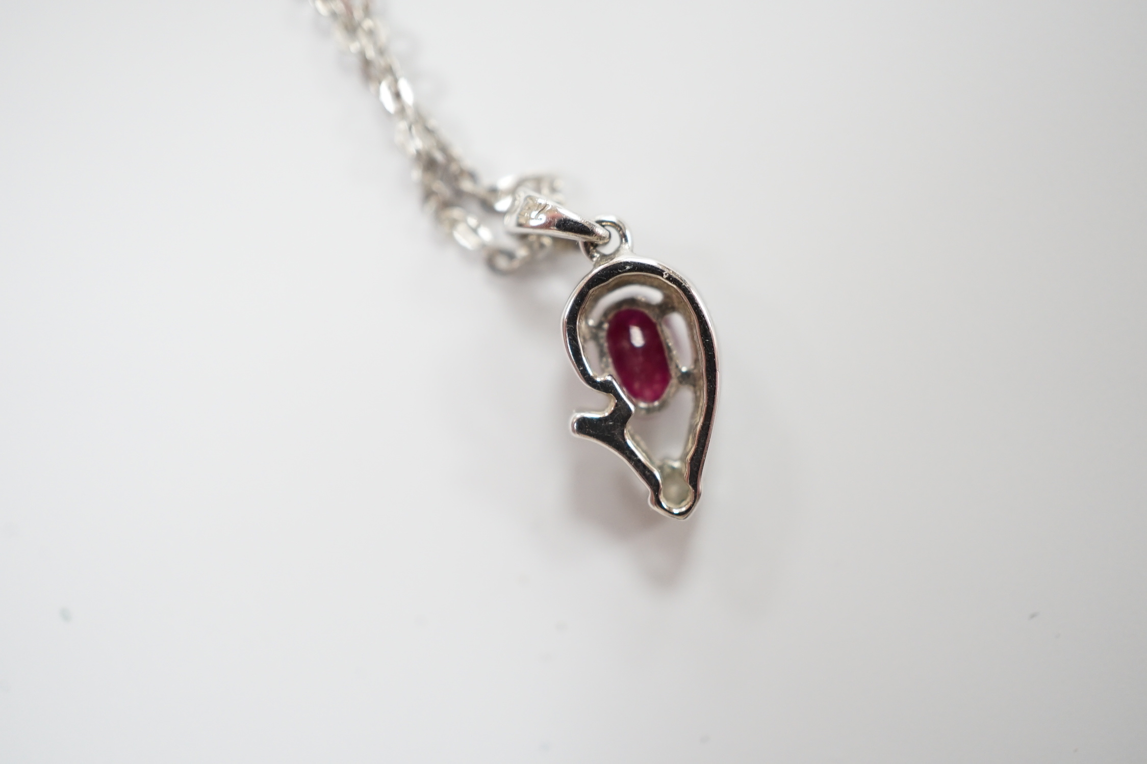 A modern 750 white metal, ruby and diamond set pendant, 9mm, on a 750 white metal chain, 42mm, gross weight 2.6 grams.